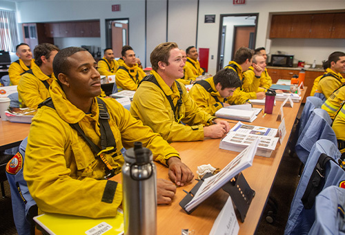 Photo of EMT students in their fire gear sitting in a classroom